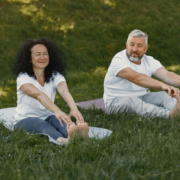 Person smiling and stretching outdoors in a green park.