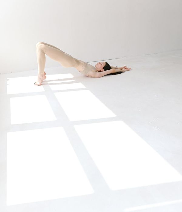 Woman in a calm yoga pose in a bright, minimalist studio.